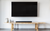 A mounted TV with no cables in the way, with a rustic wood bench located just below.