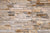 Close-up of a stone wall consisting of stacked beige and gray bricks.
