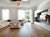 A modern design living room with a mounted tv, a white couch with red pillows, and a spherical chandelier