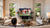 MantelMount MM815 motorized TV mount lowered above a fireplace in a living room, controlled by remote