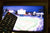Close up of a TV remote in the foreground with a blurred baseball game being shown on the TV in the background