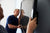Two men hold a flat screen TV against a wall and adjust it during installation.